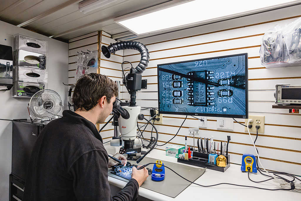 A man using a microscope to view close up of a circuit