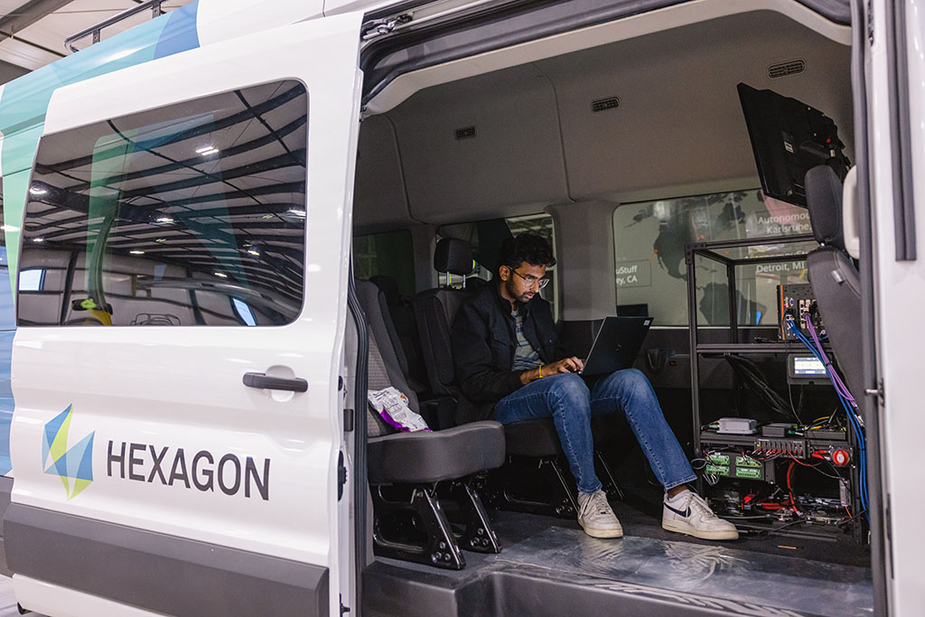 A man sitting in a vehicle working on a laptop