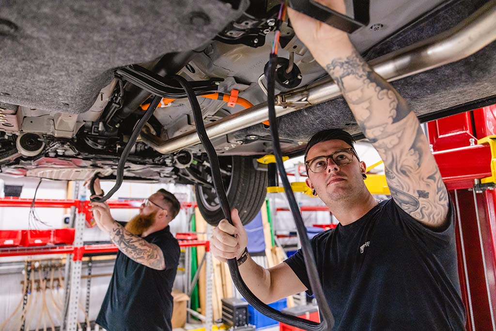 Two men working under a vehicle that has been raised