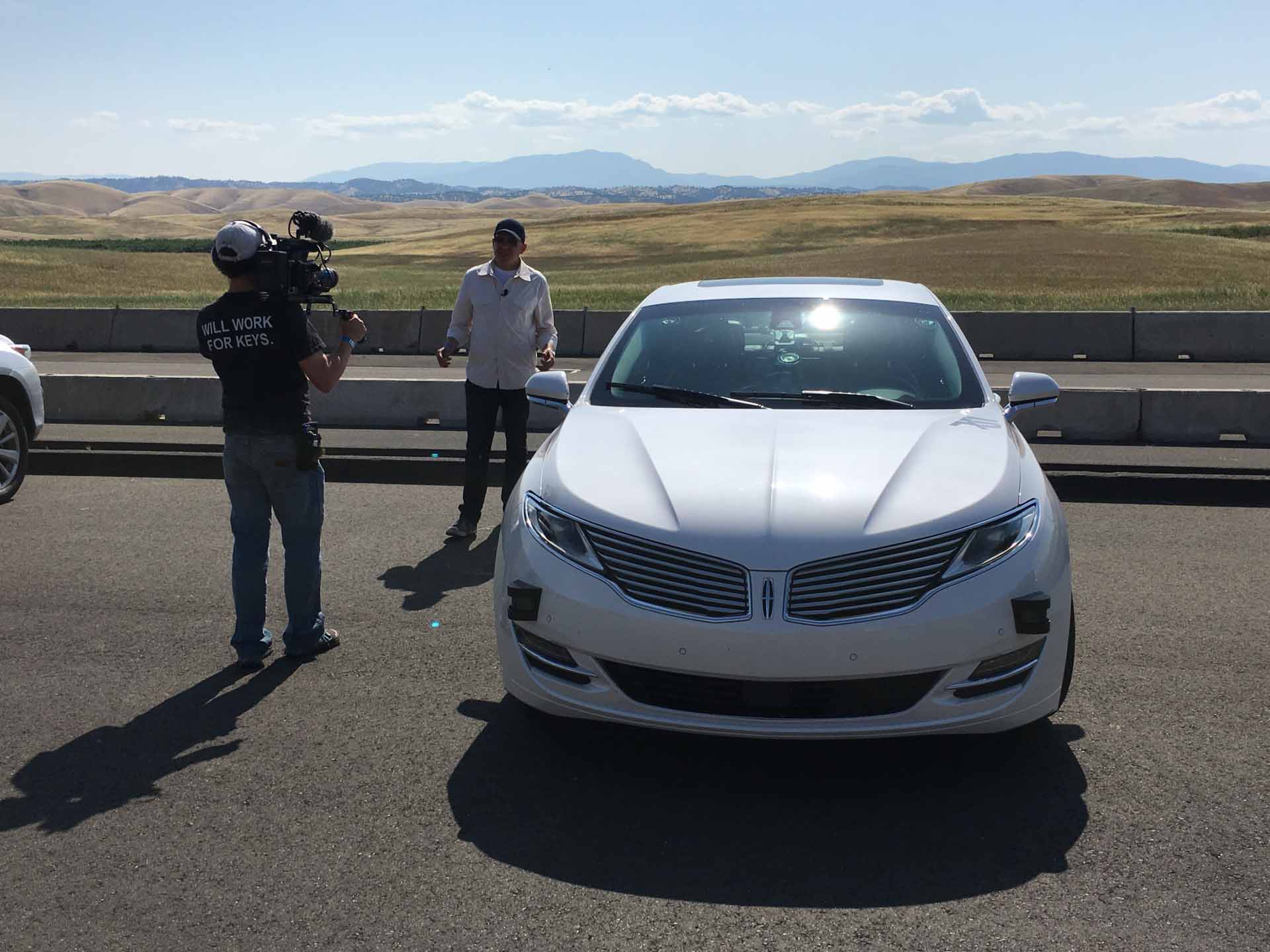 A man being interviewed on camera next to a car