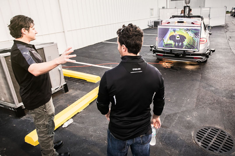 Two people looking at screen on back of vehicle