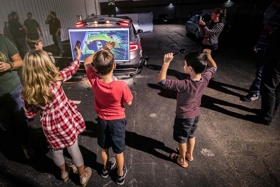 Three children watching screen on back of vehicle