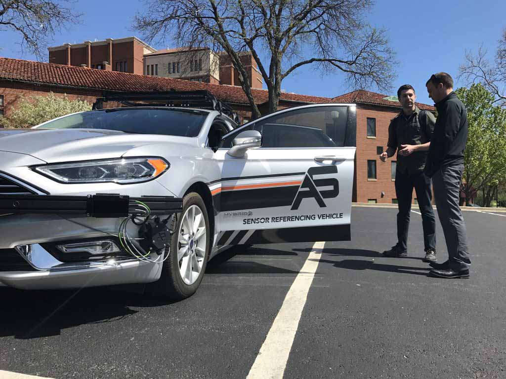 Two people standing next to vehicle with door open