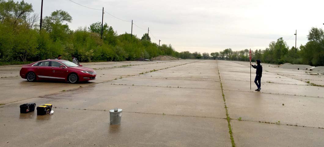 Person standing in front of a red car holding a stop sign
