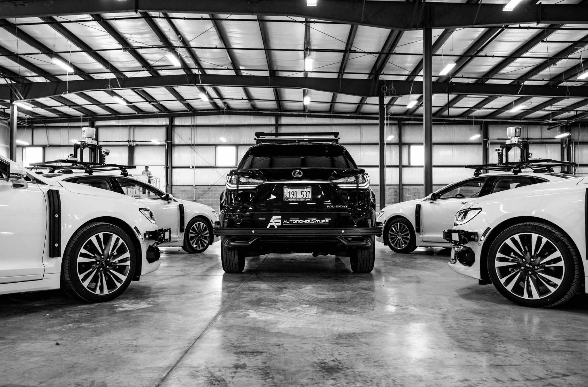 Black and white photo of rear of vehicle with other vehicles surrounding it