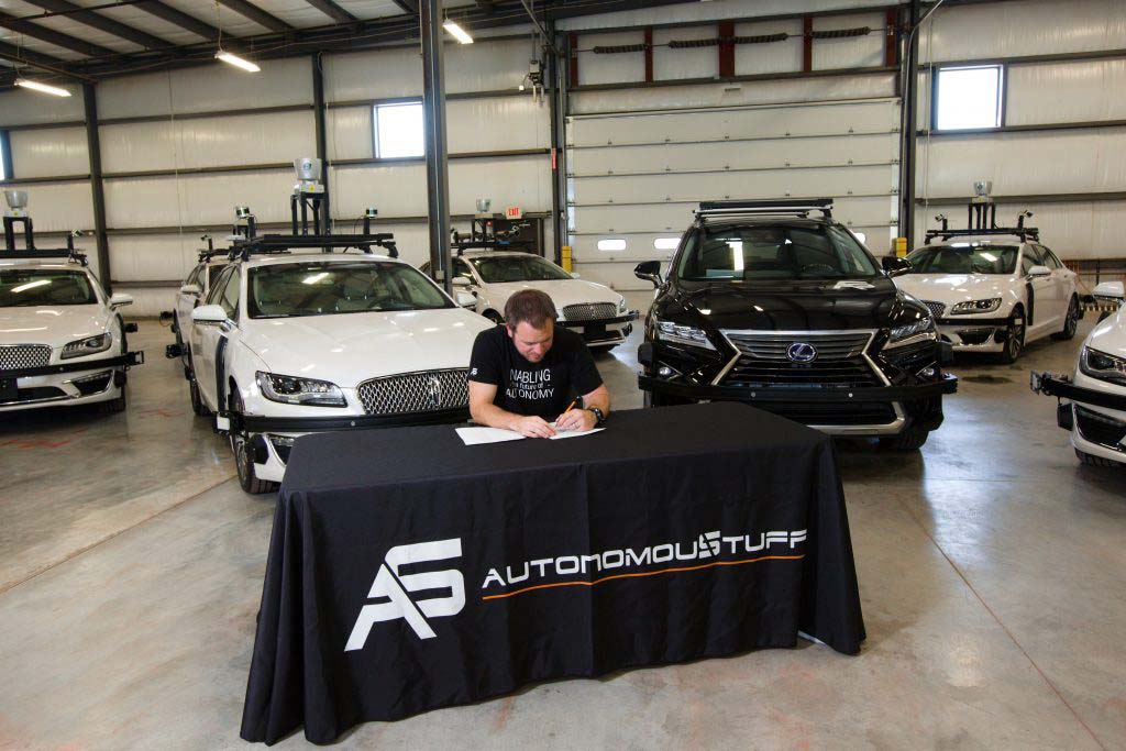 Man sitting behind a table with AutonomouStuff cloth over it