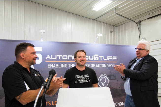 Bobby standing in front of podium and two men clapping