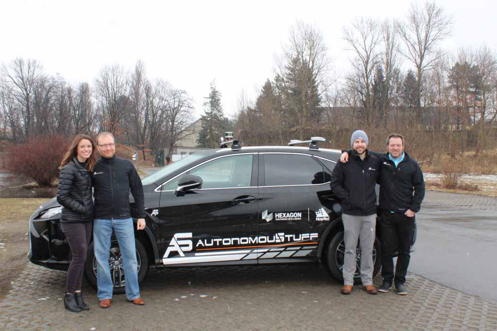 Four people standing in front of a vehicle