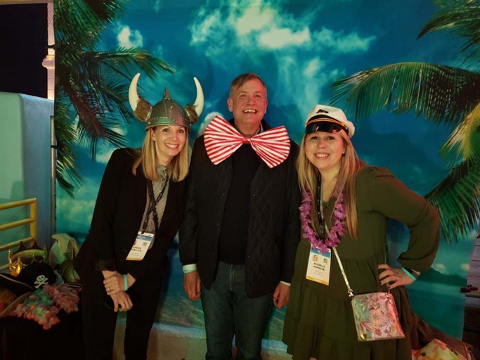 Three people posing for a photo in front of a tropical background